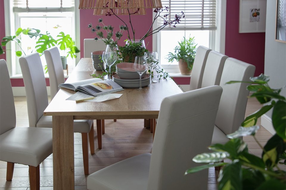 An Argos Home Miami extending oak dining table and 8 black chairs.